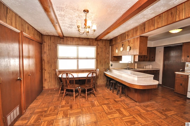 dining area featuring an inviting chandelier, wooden walls, and visible vents