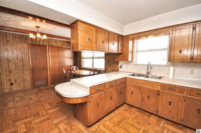 kitchen with brown cabinetry, a peninsula, light countertops, and a sink