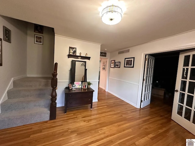 corridor with wood finished floors, visible vents, baseboards, french doors, and stairway