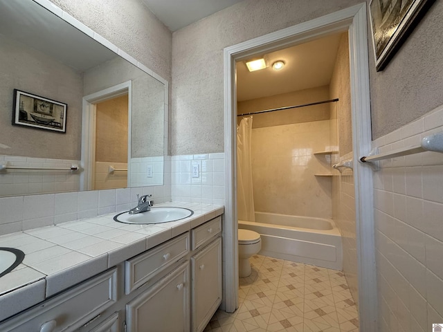 full bath with toilet, vanity, tile walls, tile patterned floors, and shower / bathtub combination with curtain