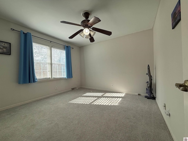 spare room featuring baseboards, a ceiling fan, and light colored carpet