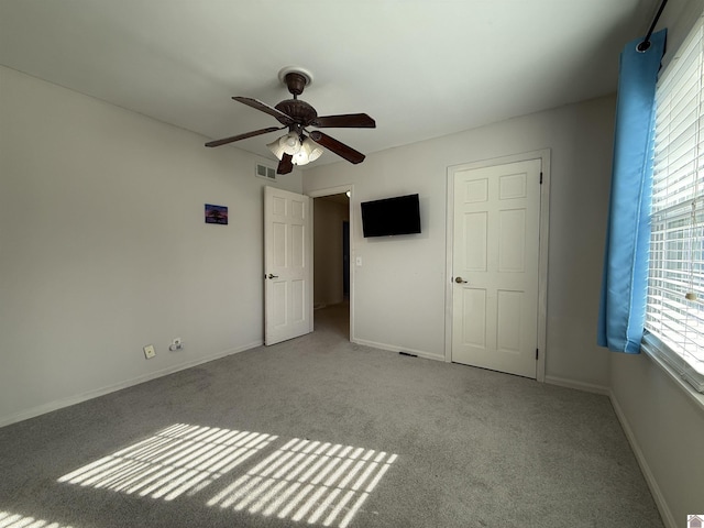 unfurnished bedroom with light carpet, baseboards, visible vents, and ceiling fan