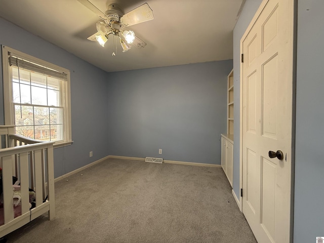 unfurnished bedroom with carpet floors, visible vents, baseboards, and a ceiling fan