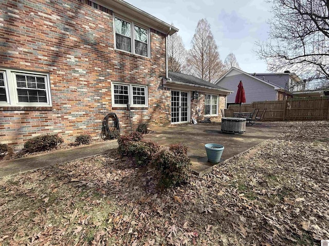 back of house with brick siding, fence, and a patio