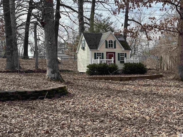 new england style home featuring roof with shingles and fence