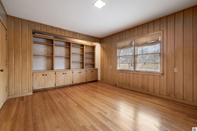 empty room with wooden walls and light wood-style flooring