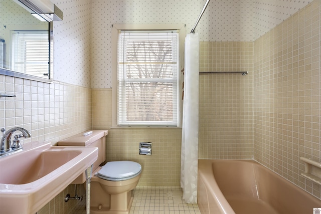 full bath with a wealth of natural light, a sink, tile walls, and tile patterned floors