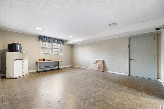 unfurnished room featuring concrete block wall, visible vents, and a textured ceiling