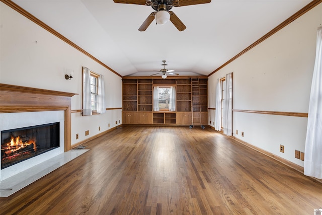 unfurnished living room featuring built in shelves, a glass covered fireplace, vaulted ceiling, and wood finished floors