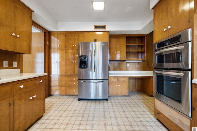 kitchen featuring light countertops, appliances with stainless steel finishes, and brown cabinets