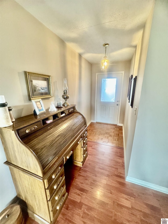 entryway with a textured ceiling, wood finished floors, and baseboards