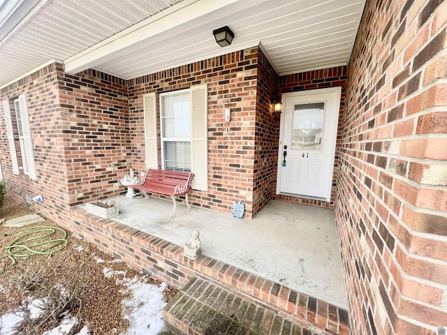 snow covered property entrance featuring brick siding