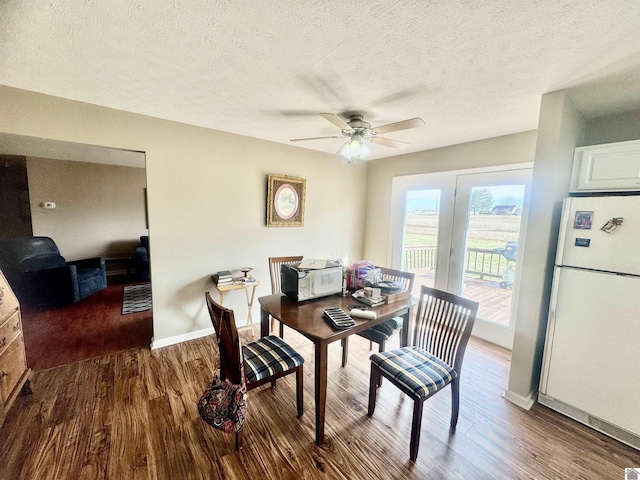 dining space featuring ceiling fan, a textured ceiling, baseboards, and wood finished floors