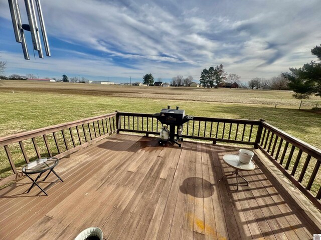 wooden terrace with a grill, a lawn, and a rural view