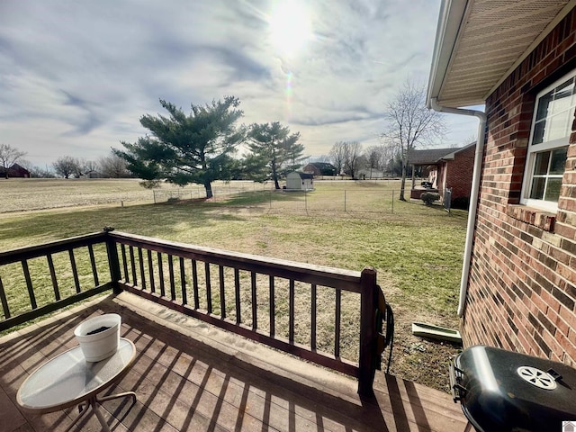 deck with fence, a lawn, and a rural view