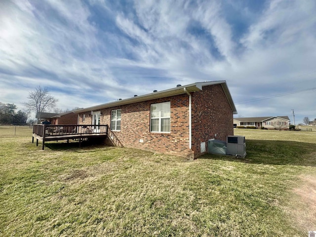 view of side of home featuring a deck, brick siding, and a lawn