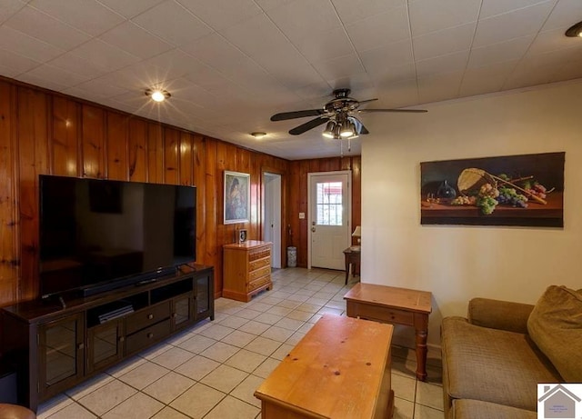 living room featuring ceiling fan, wooden walls, and light tile patterned floors