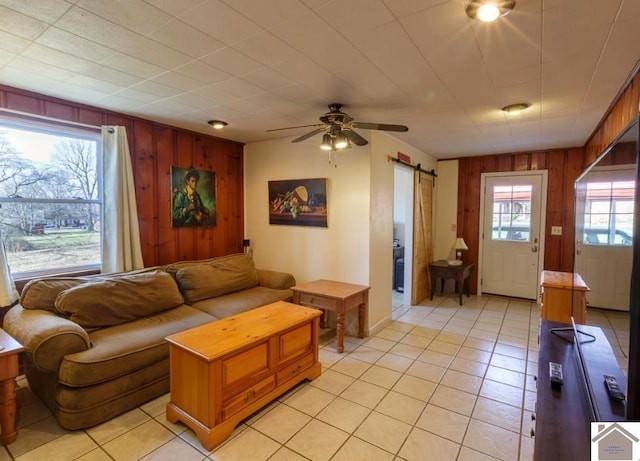 living room featuring a barn door, plenty of natural light, and wooden walls