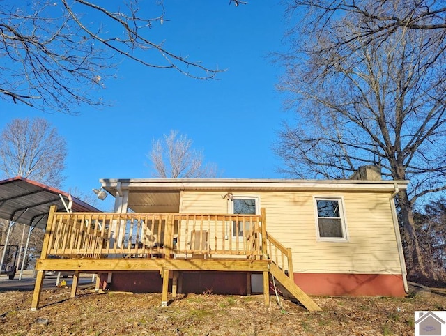 back of house featuring a chimney, a wooden deck, and a detached carport