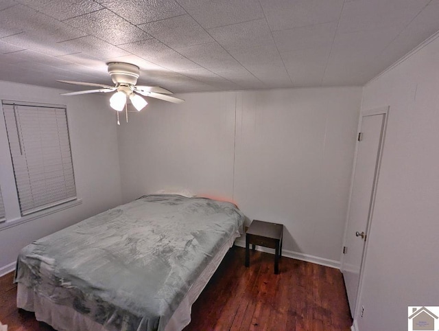 bedroom with dark wood-style floors, a ceiling fan, and baseboards