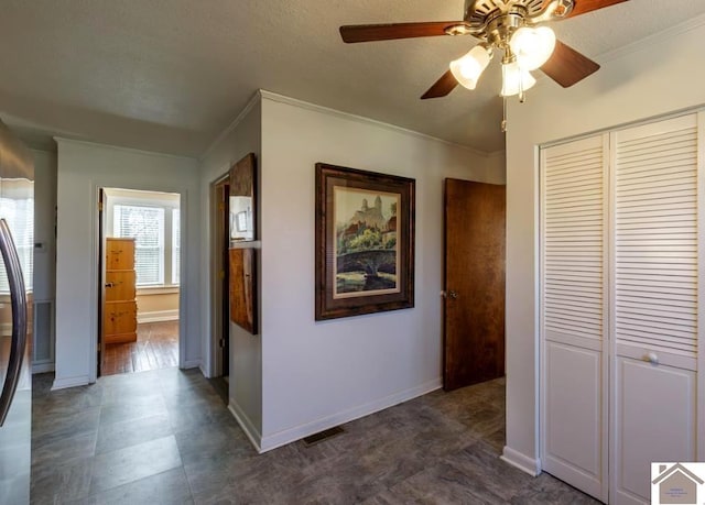 hallway featuring baseboards, a textured ceiling, visible vents, and crown molding