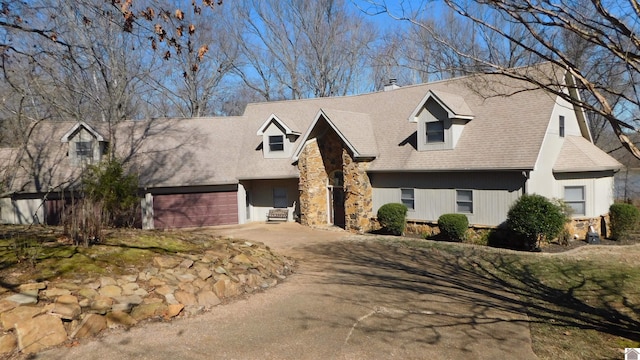 cape cod home featuring driveway and stone siding