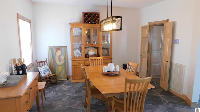 dining space with dark tile patterned flooring, visible vents, and baseboards