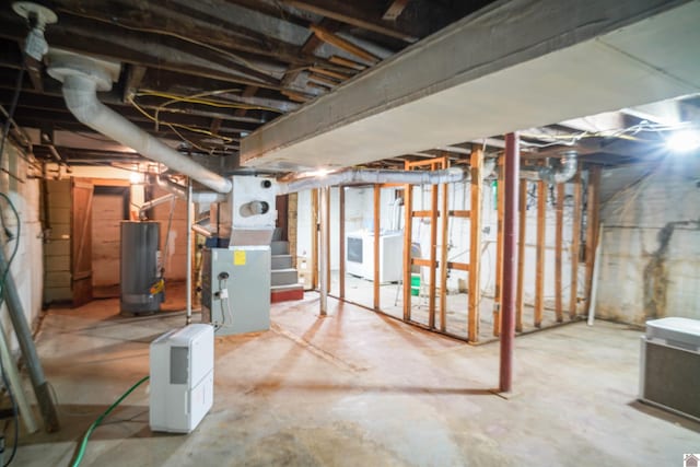 unfinished below grade area with water heater, washer / dryer, and heating unit