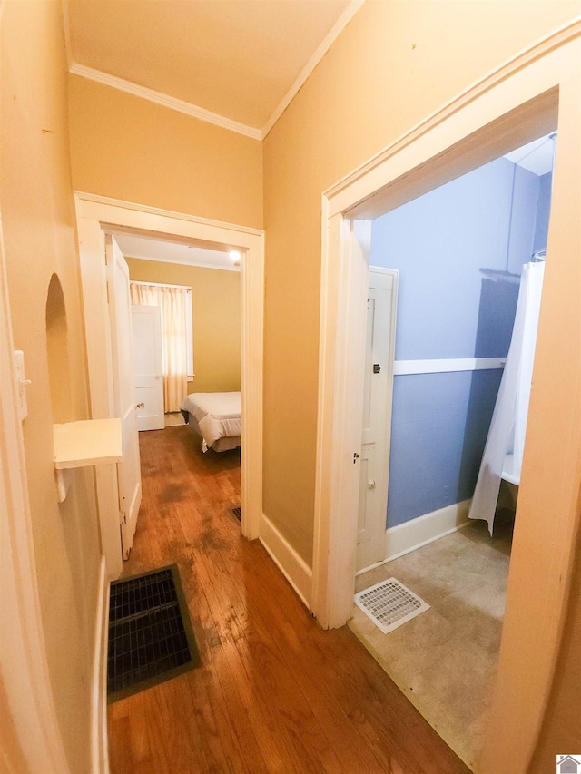 hall with visible vents, crown molding, baseboards, and wood finished floors