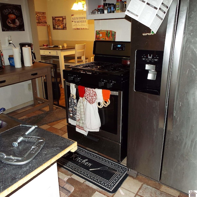 kitchen with stainless steel refrigerator with ice dispenser and black range with gas stovetop