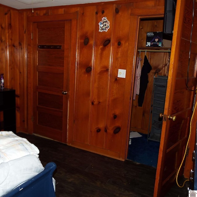 bedroom with dark wood-style floors, a closet, and wood walls