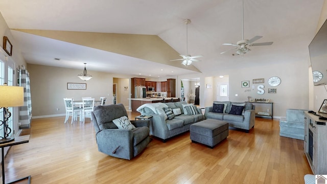 living area featuring light wood finished floors, baseboards, and high vaulted ceiling