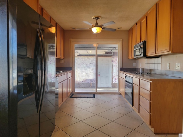 kitchen with brown cabinets, light countertops, light tile patterned flooring, a textured ceiling, and black appliances