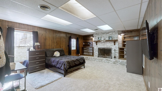 bedroom featuring multiple windows, a brick fireplace, visible vents, and wooden walls