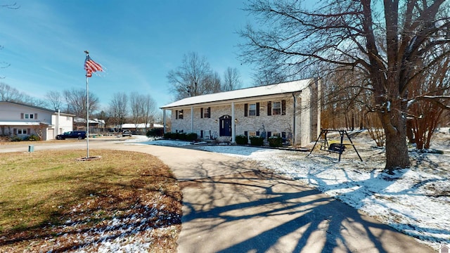 raised ranch featuring concrete driveway and a yard