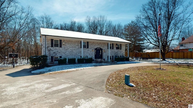 split foyer home featuring concrete driveway and fence