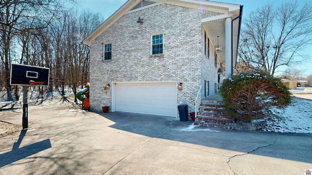 view of home's exterior with a garage, concrete driveway, and brick siding