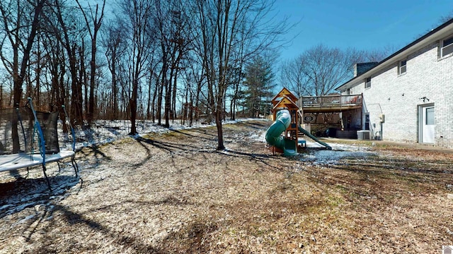 yard layered in snow with a trampoline, cooling unit, and playground community