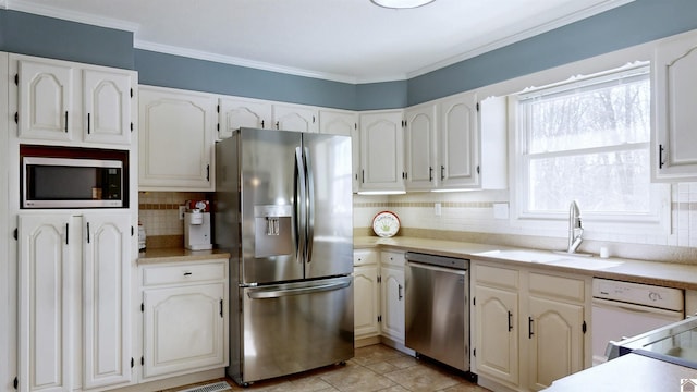 kitchen featuring appliances with stainless steel finishes, light countertops, a sink, and ornamental molding