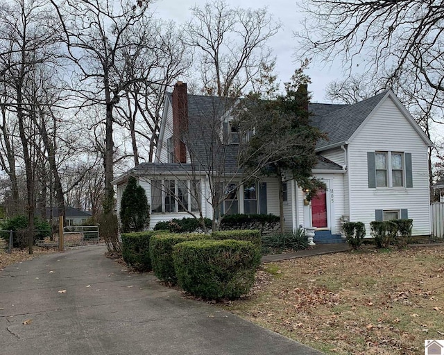 view of front of home featuring roof with shingles, fence, and a chimney