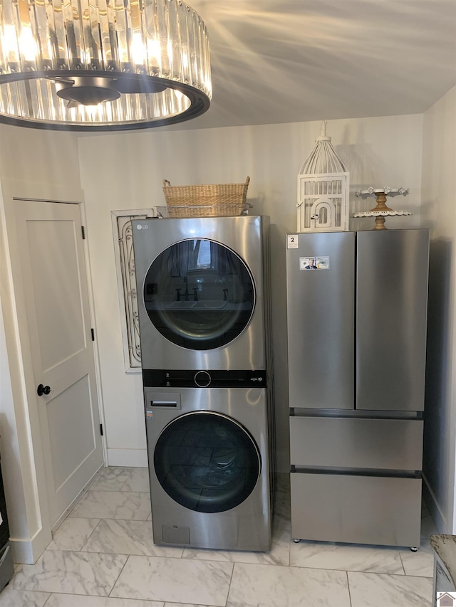 clothes washing area featuring stacked washer / drying machine, marble finish floor, baseboards, and laundry area