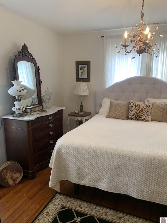 bedroom with an inviting chandelier and wood finished floors