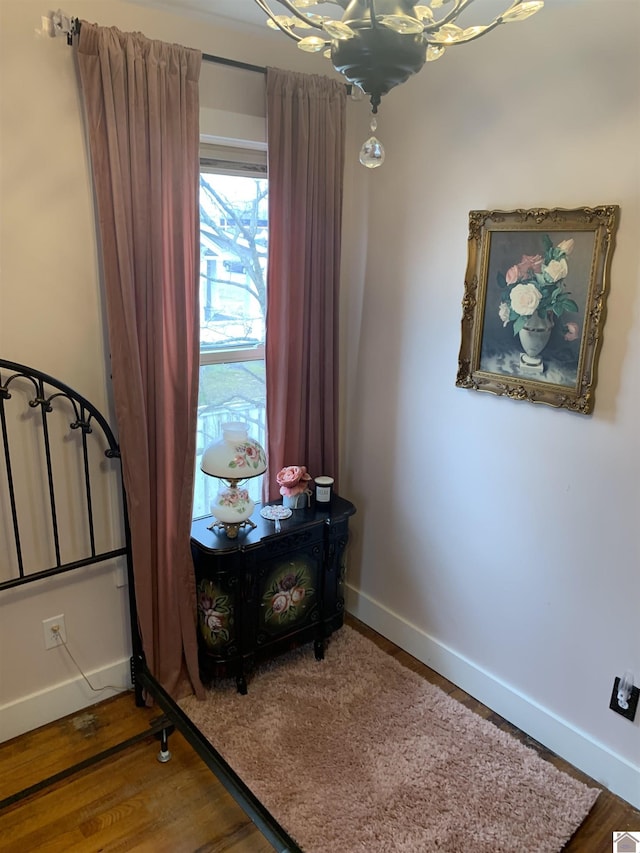 interior space with an inviting chandelier, wood finished floors, and baseboards