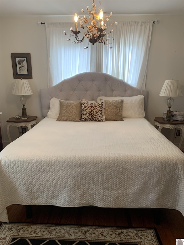 bedroom with a notable chandelier and wood finished floors