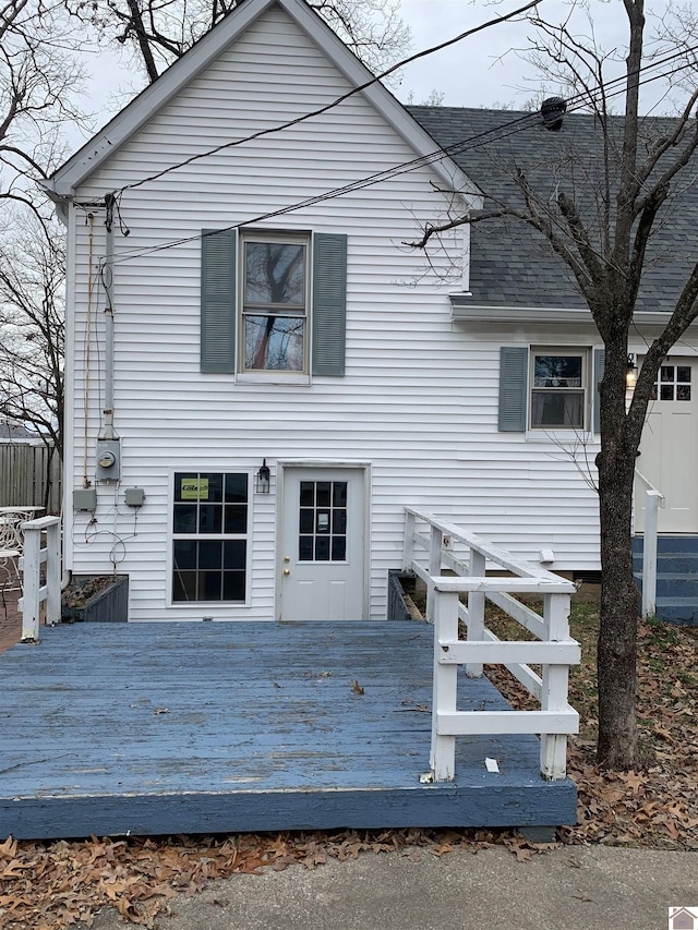 exterior space with a shingled roof and a deck