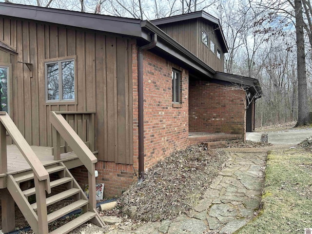 view of side of property featuring brick siding, board and batten siding, and stairway