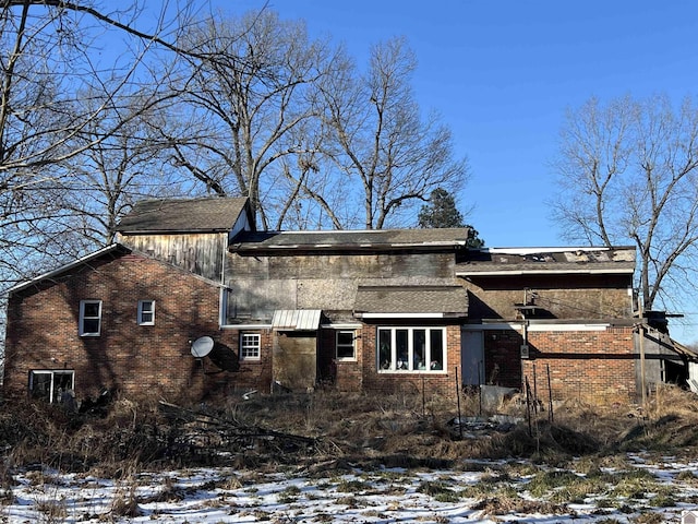 view of snowy exterior featuring brick siding