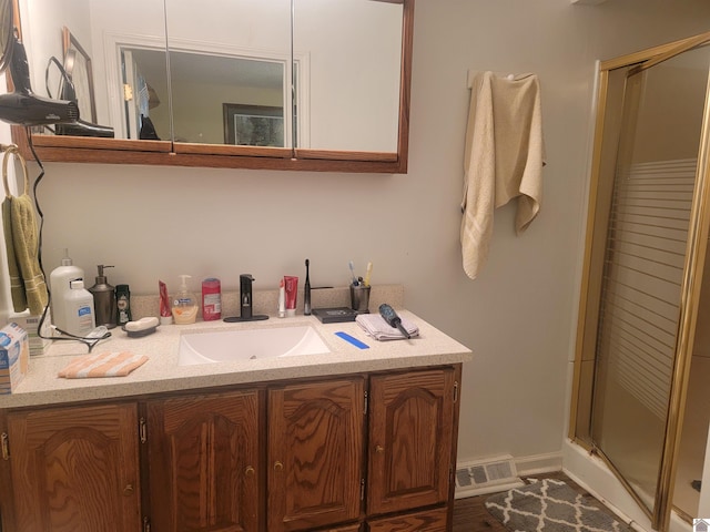 bathroom with visible vents, vanity, and a shower stall