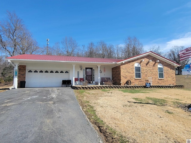 ranch-style house featuring a garage, metal roof, aphalt driveway, a porch, and brick siding