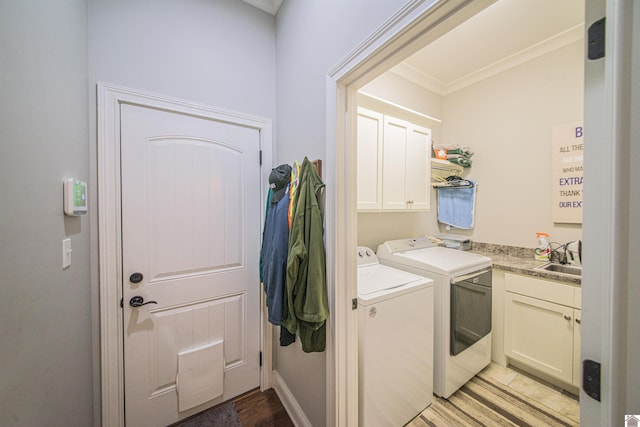 clothes washing area with cabinet space, a sink, light wood finished floors, and washing machine and clothes dryer